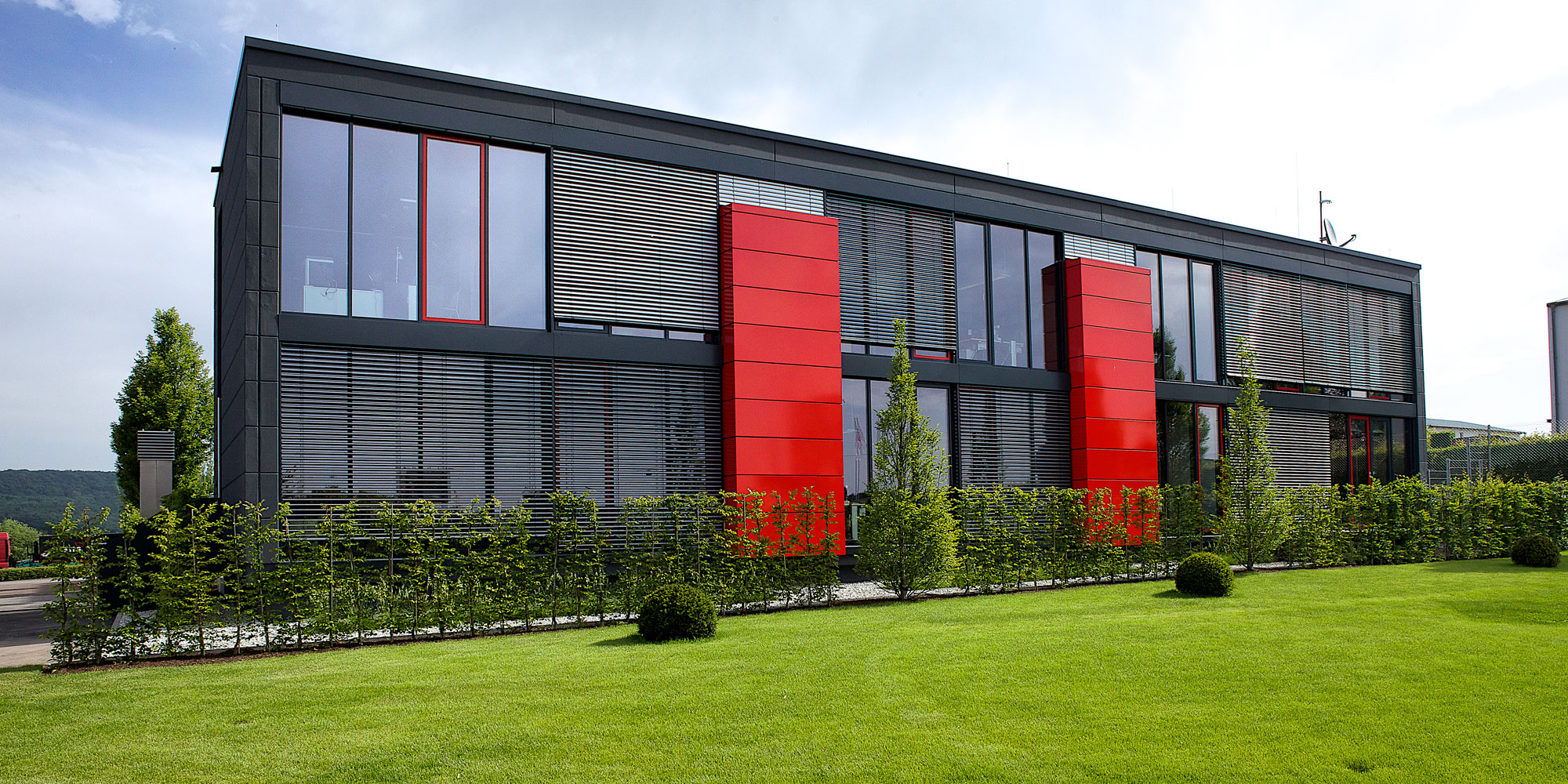 Anthrazitfarbenes Bürogebäude mit roten Fassaden-Akzenten von hebelHALLE