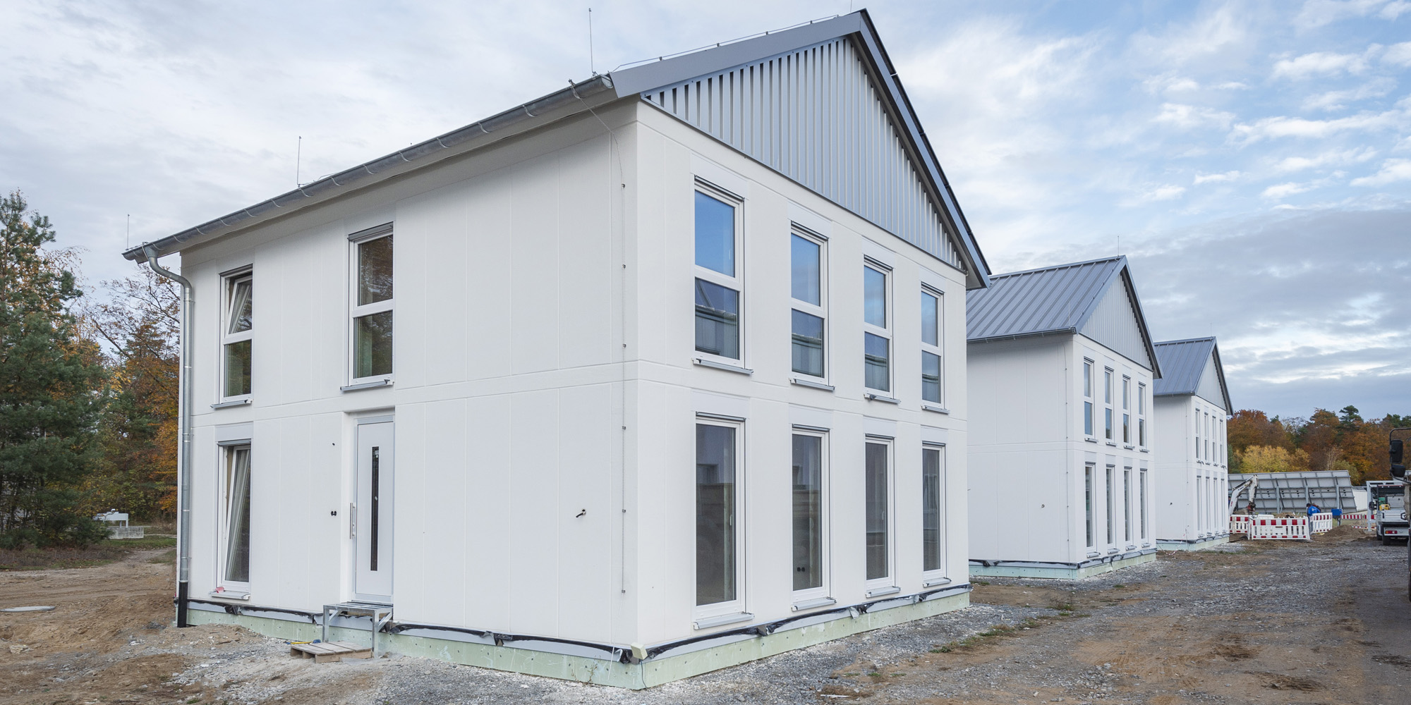 Drei baugleiche Einfamilienhäuser aus weißem Porenbeton mit Satteldach und Festerfront von hebelHALLE