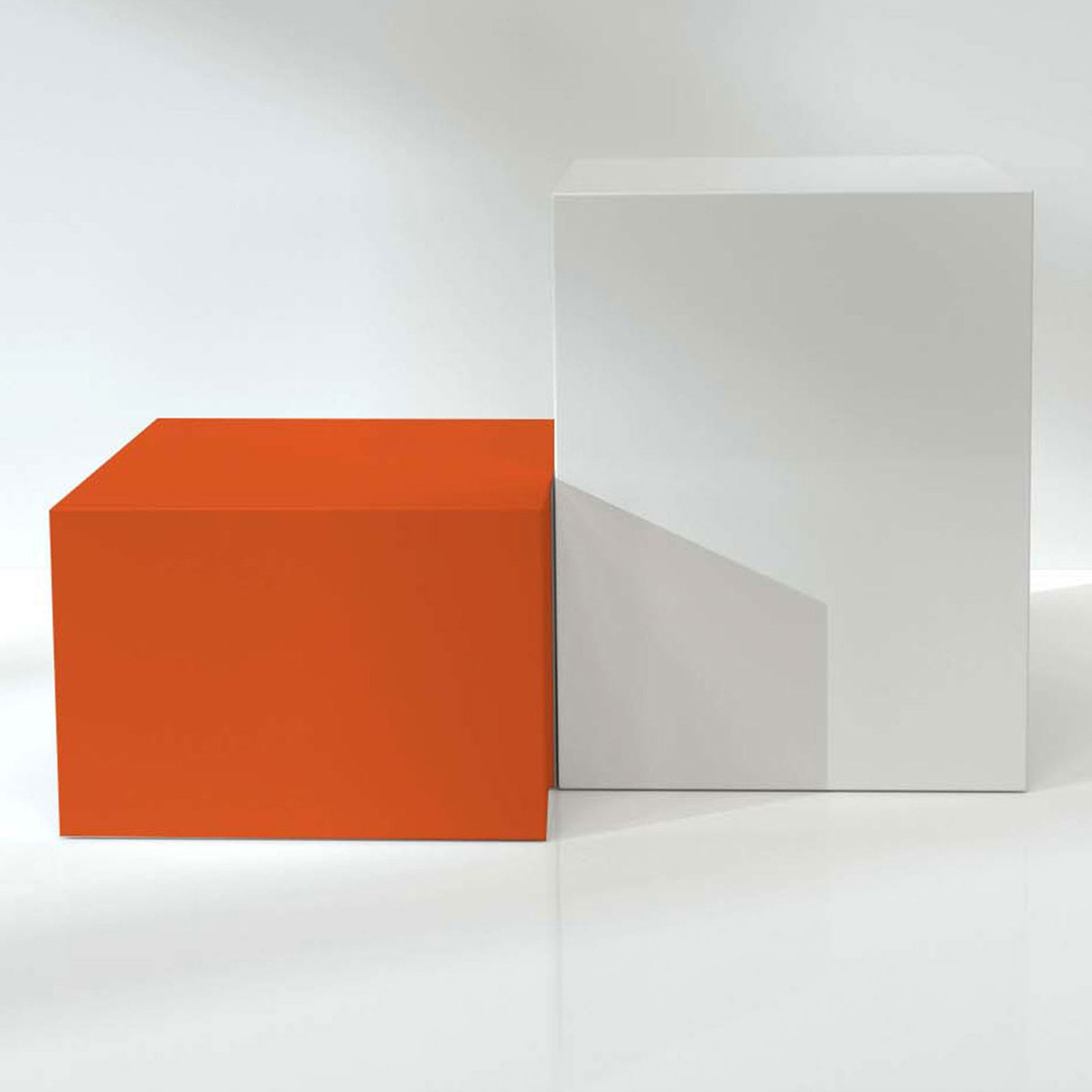 Ein kleiner orangener Klotz steht neben einem großen weißen Klotz auf spiegelnder Oberfläche